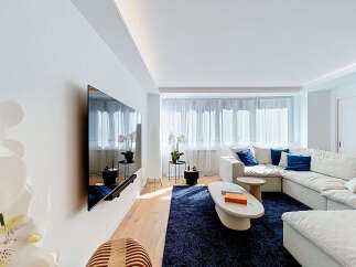 Experience modern living in this bright and airy living room, featuring a large sectional sofa adorned with plush blue accent pillows.