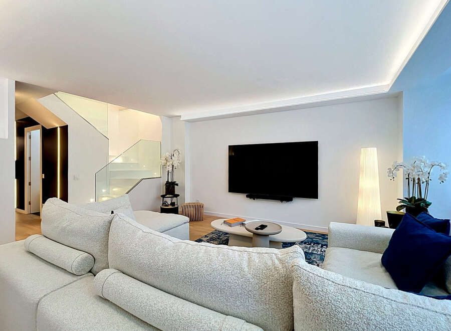 Experience modern luxury in this stunning living room featuring a sleek entertainment setup with a large flat-screen TV mounted above a minimalist coffee table.