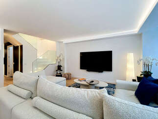 Experience modern luxury in this stunning living room featuring a sleek entertainment setup with a large flat-screen TV mounted above a minimalist coffee table.
