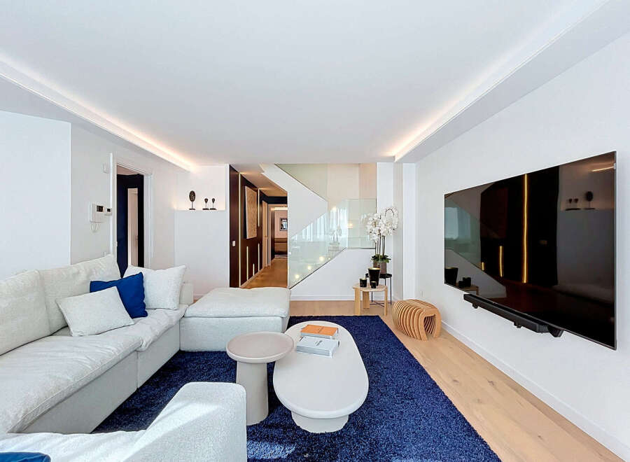 Experience modern luxury in this spacious living room featuring a large, comfortable sectional sofa and a vibrant blue rug.
