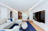 Experience modern luxury in this spacious living room featuring a large, comfortable sectional sofa and a vibrant blue rug.