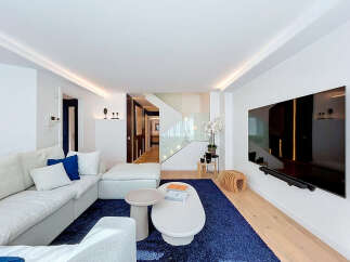 Experience modern luxury in this spacious living room featuring a large, comfortable sectional sofa and a vibrant blue rug.