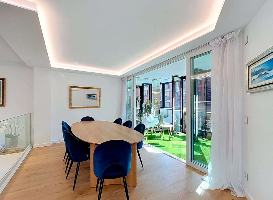 Experience modern living in this elegant dining area, featuring a sleek oval wooden table surrounded by plush navy velvet chairs.