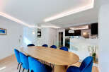Experience modern luxury in this stunning dining area, featuring a sleek, oval-shaped wooden table complemented by vibrant blue velvet chairs.