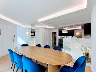 Experience modern luxury in this stunning dining area, featuring a sleek, oval-shaped wooden table complemented by vibrant blue velvet chairs.
