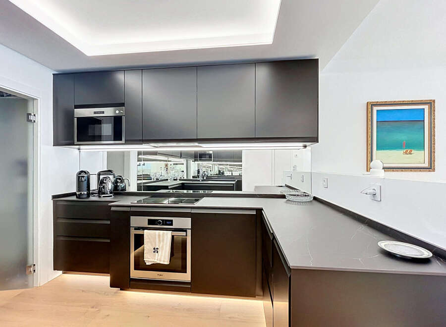 Experience modern luxury in this sleek kitchen, featuring dark cabinetry, integrated appliances including a microwave and oven, and a stylish induction cooktop.