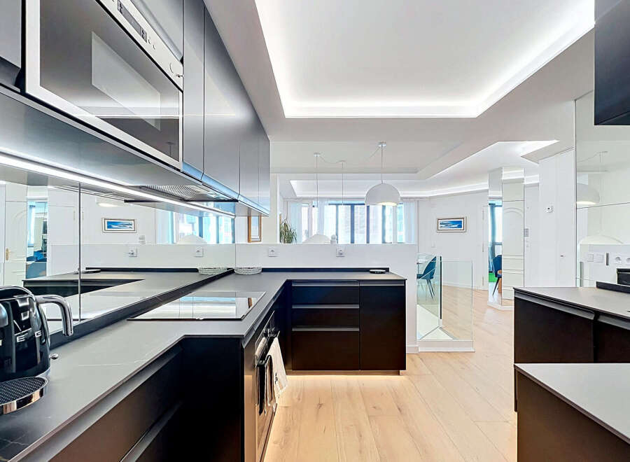 Experience modern luxury in this sleek, contemporary kitchen featuring dark cabinetry, integrated appliances, and a stunning reflective backsplash.