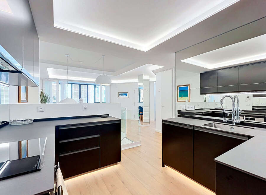 Experience modern luxury in this stunning open-concept kitchen, featuring sleek dark cabinetry and a pristine white countertop.