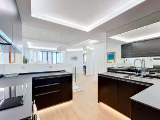 Experience modern luxury in this stunning open-concept kitchen, featuring sleek dark cabinetry and a pristine white countertop.