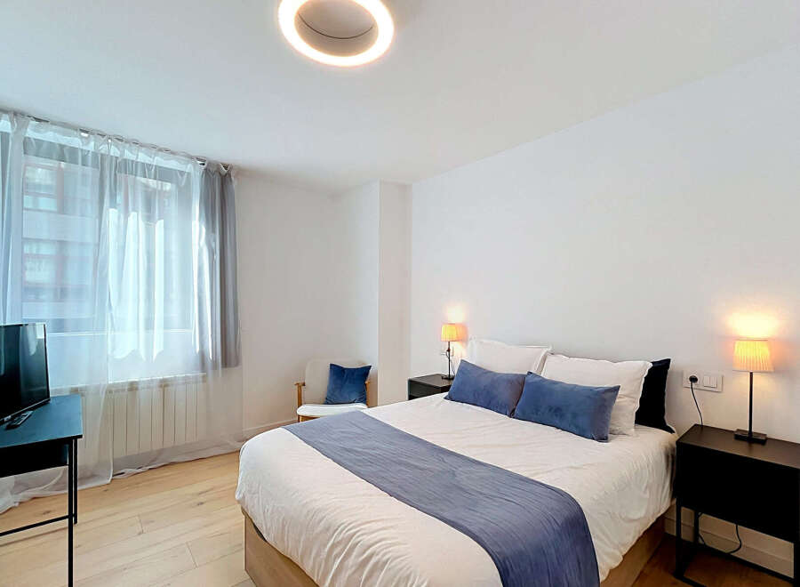Experience comfort and style in this beautifully appointed bedroom, featuring a plush king-size bed adorned with crisp white linens and elegant blue accent pillows.