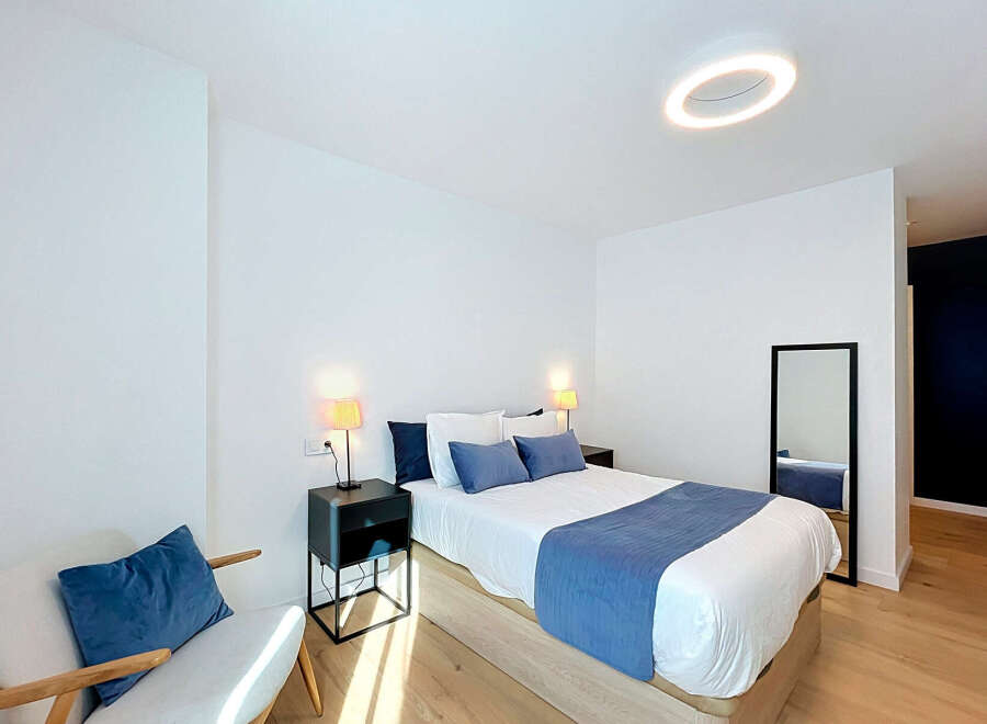 Experience modern comfort in this beautifully appointed bedroom, featuring a plush queen-size bed adorned with crisp white linens and accented by a stylish blue throw.