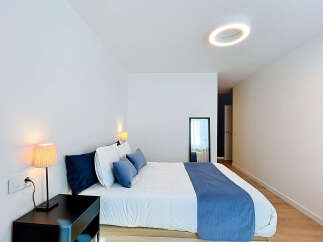 Experience modern comfort in this beautifully appointed bedroom, featuring a plush king-sized bed adorned with crisp white linens and elegant blue accent pillows.