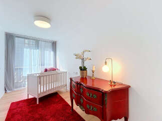 This charming nursery features a cozy white crib set against a vibrant red rug, creating a playful and inviting atmosphere.