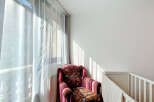 Bright and airy, this cozy corner features a vibrantly patterned armchair bathed in natural light streaming through sheer curtains.