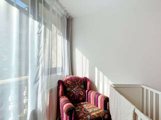 Bright and airy, this cozy corner features a vibrantly patterned armchair bathed in natural light streaming through sheer curtains.