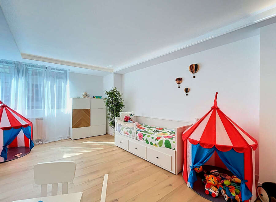 This charming children's bedroom features a playful circus-themed tent and a comfortable daybed adorned with a vibrant floral comforter.