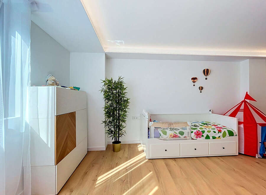 This charming children's room features a comfortable white daybed with colorful floral bedding, perfect for a child's sanctuary.