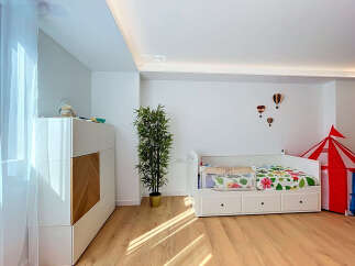 This charming children's room features a comfortable white daybed with colorful floral bedding, perfect for a child's sanctuary.