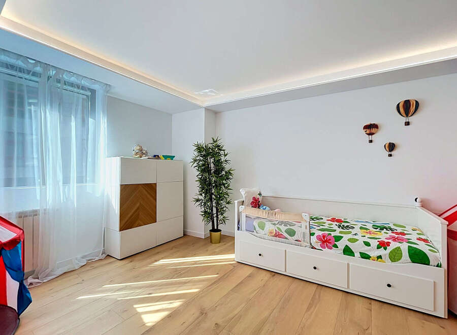 This charming children's bedroom features a bright and airy atmosphere, enhanced by natural light streaming through sheer curtains.