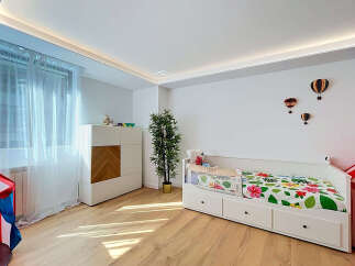 This charming children's bedroom features a bright and airy atmosphere, enhanced by natural light streaming through sheer curtains.