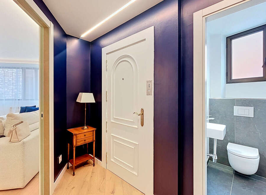 Step into a stylish entryway featuring a striking deep purple accent wall and elegant white door.