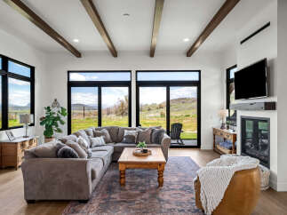 Experience luxury living in this stunning property featuring a spacious living room with expansive windows that offer breathtaking views of the surrounding landscape.