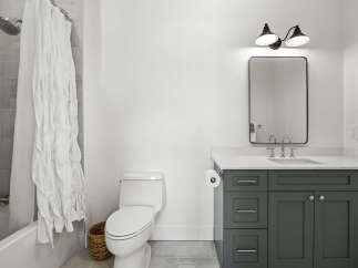 This modern bathroom features a sleek design with a gray vanity and a white countertop.