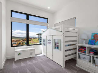 This charming bedroom features a unique house-shaped bunk bed, perfect for imaginative play and cozy nights.