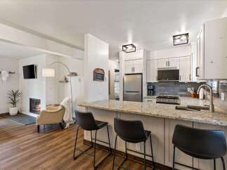 This stunning property boasts a modern kitchen with granite countertops and sleek black bar stools, perfect for entertaining.