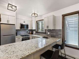 This stunning kitchen boasts a modern design with sleek white cabinetry and a beautiful granite countertop, perfect for meal preparation and entertaining.