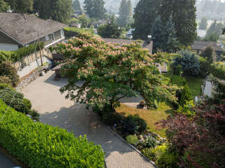 This stunning property boasts a beautifully landscaped yard with a large, mature tree providing ample shade.