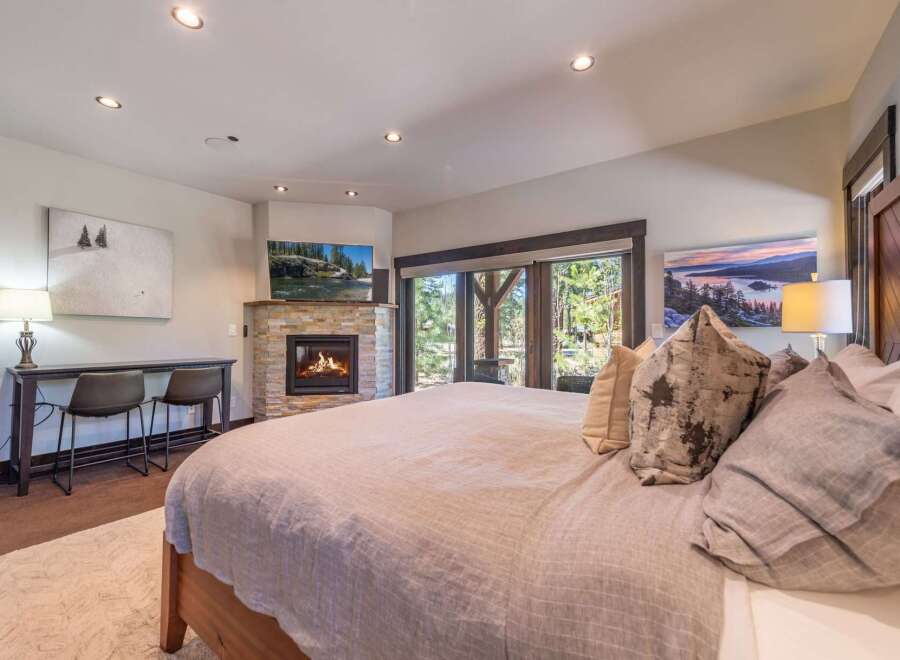 Experience luxury in this stunning bedroom featuring a cozy fireplace and a large bed, perfect for relaxation.
