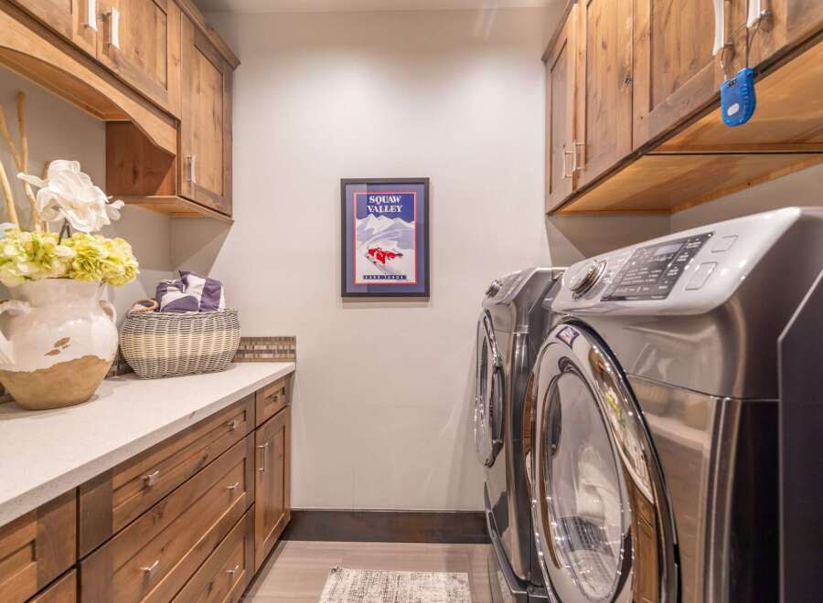 This stunning laundry room boasts custom cabinetry and a sleek countertop, perfect for organizing and folding laundry.