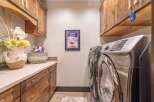 This stunning laundry room boasts custom cabinetry and a sleek countertop, perfect for organizing and folding laundry.