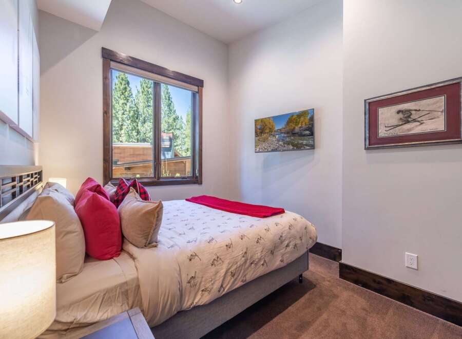 This cozy bedroom features a comfortable bed adorned with stylish pillows and a vibrant red throw, creating a warm and inviting atmosphere.
