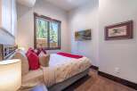 This cozy bedroom features a comfortable bed adorned with stylish pillows and a vibrant red throw, creating a warm and inviting atmosphere.