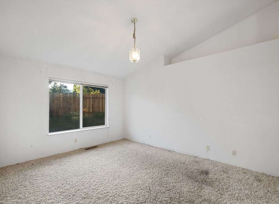 This inviting room features a large window that allows natural light to flood the space, highlighting the plush carpeting.