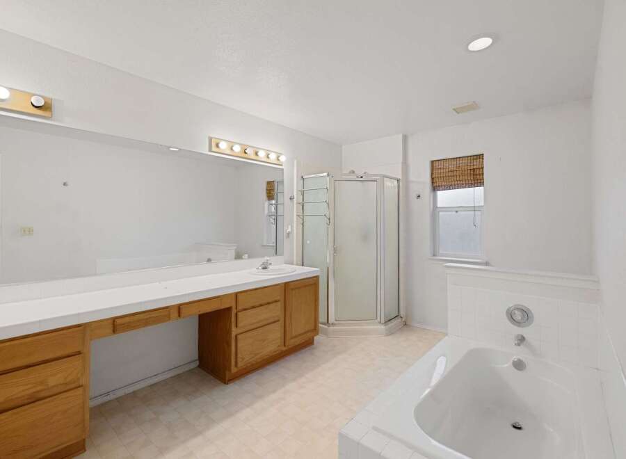 Step into this bright and airy bathroom, featuring a spacious vanity with ample storage and a large mirror.