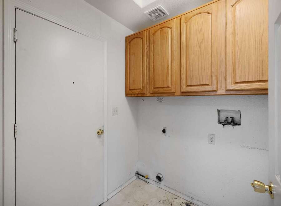 This laundry room features ample storage with overhead cabinets, perfect for organizing cleaning supplies.