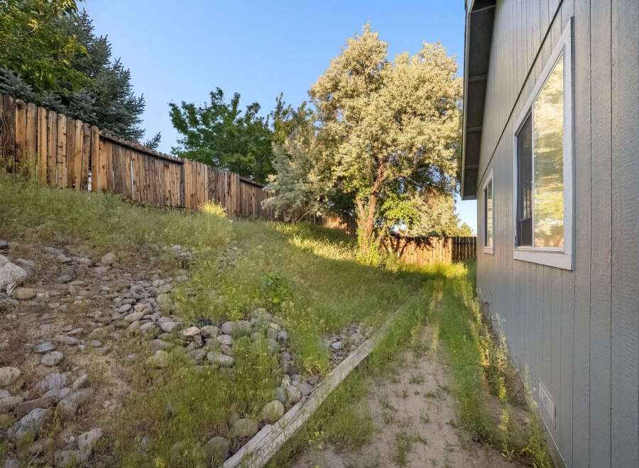 Discover the charm of this property, featuring a serene backyard with a wooden fence and lush greenery.