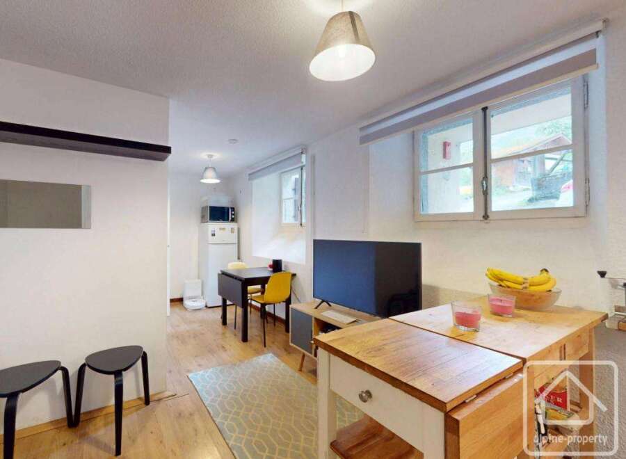Discover this charming property featuring a cozy living space with a modern TV and a well-equipped kitchen area.