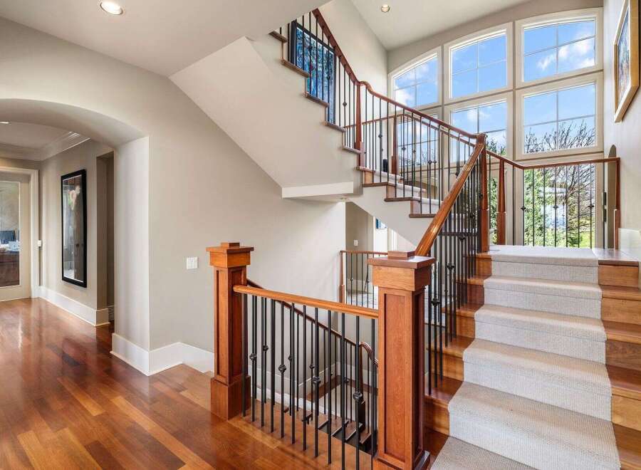 This stunning property boasts a grand staircase with elegant wooden accents and intricate wrought iron railings.