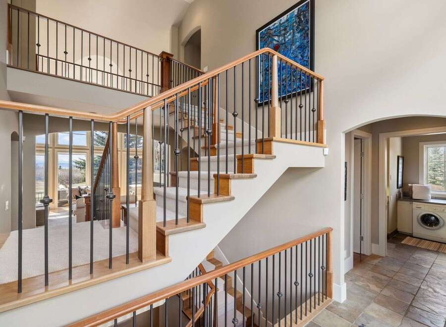 This stunning property boasts a grand staircase with elegant iron railings and warm wooden accents, creating a welcoming first impression.