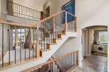 This stunning property boasts a grand staircase with elegant iron railings and warm wooden accents, creating a welcoming first impression.