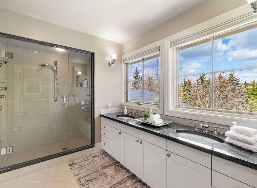 Step into luxury with this stunning bathroom featuring a sleek glass shower and a double vanity with a granite countertop.