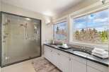 Step into luxury with this stunning bathroom featuring a sleek glass shower and a double vanity with a granite countertop.