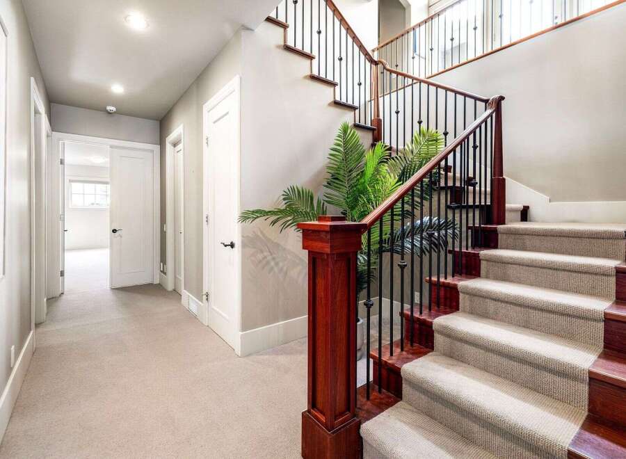 This stunning property features a grand staircase with elegant wooden accents and wrought iron railings.