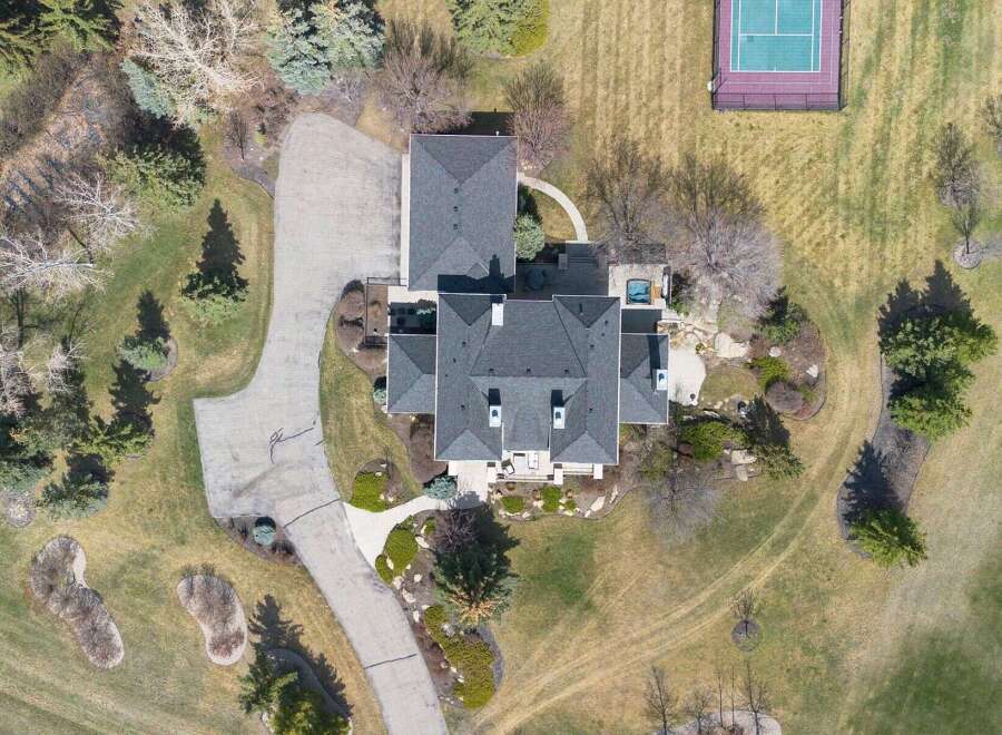 An aerial view showcases a luxurious estate featuring a sprawling driveway leading to a grand residence.