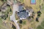 An aerial view showcases a luxurious estate featuring a sprawling driveway leading to a grand residence.