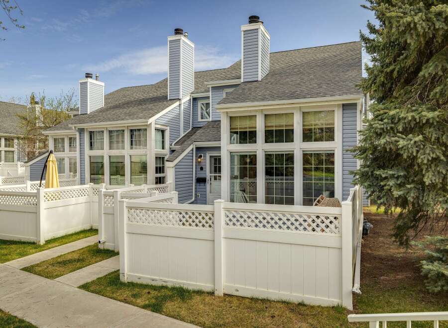 Discover this charming townhome featuring a beautiful exterior with a light blue siding and a white fence.